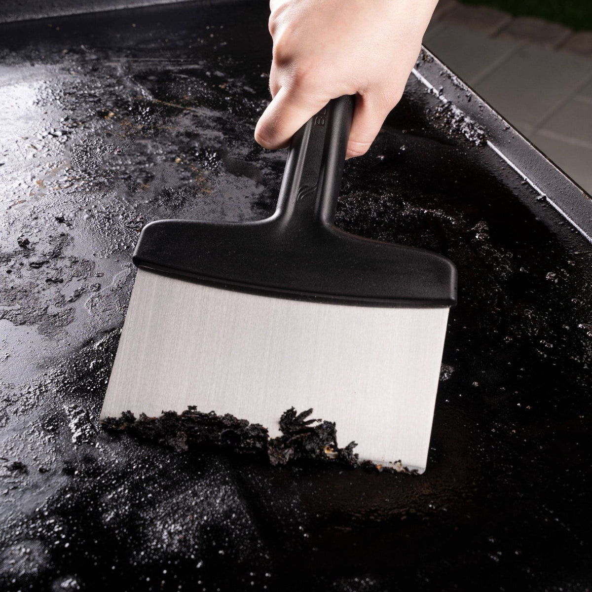 Blackstone 5-piece griddle toolkit, scraper cleaning the griddle top