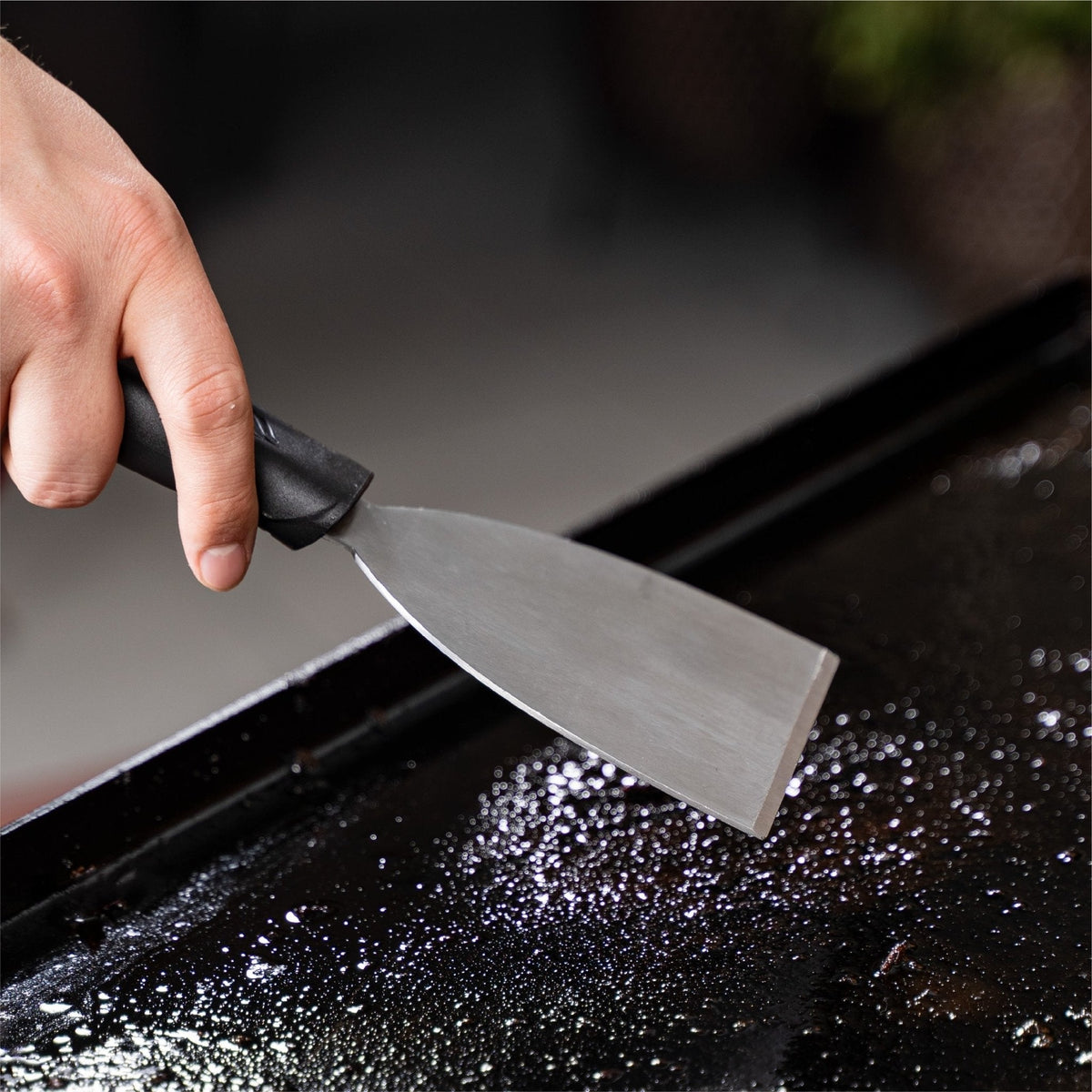 Blackstone griddle cleaning kit, scraper clearing the griddle top