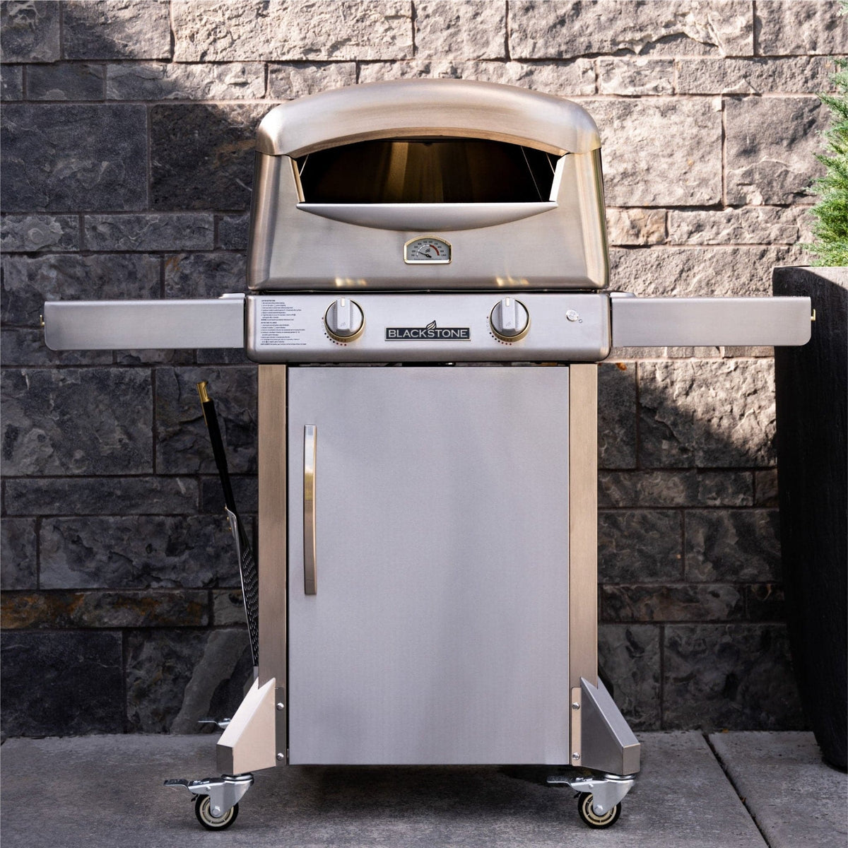 Blackstone Select pizza oven with cart, on a stone patio