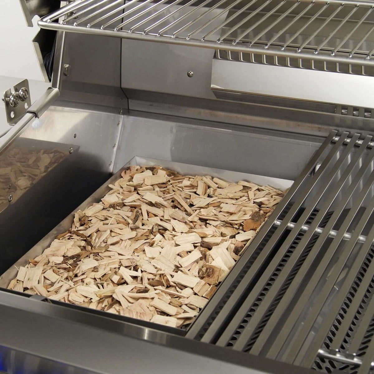 Wood chip smoker basket set on the cooking grates of the Fire Magic Echelon E1060i
